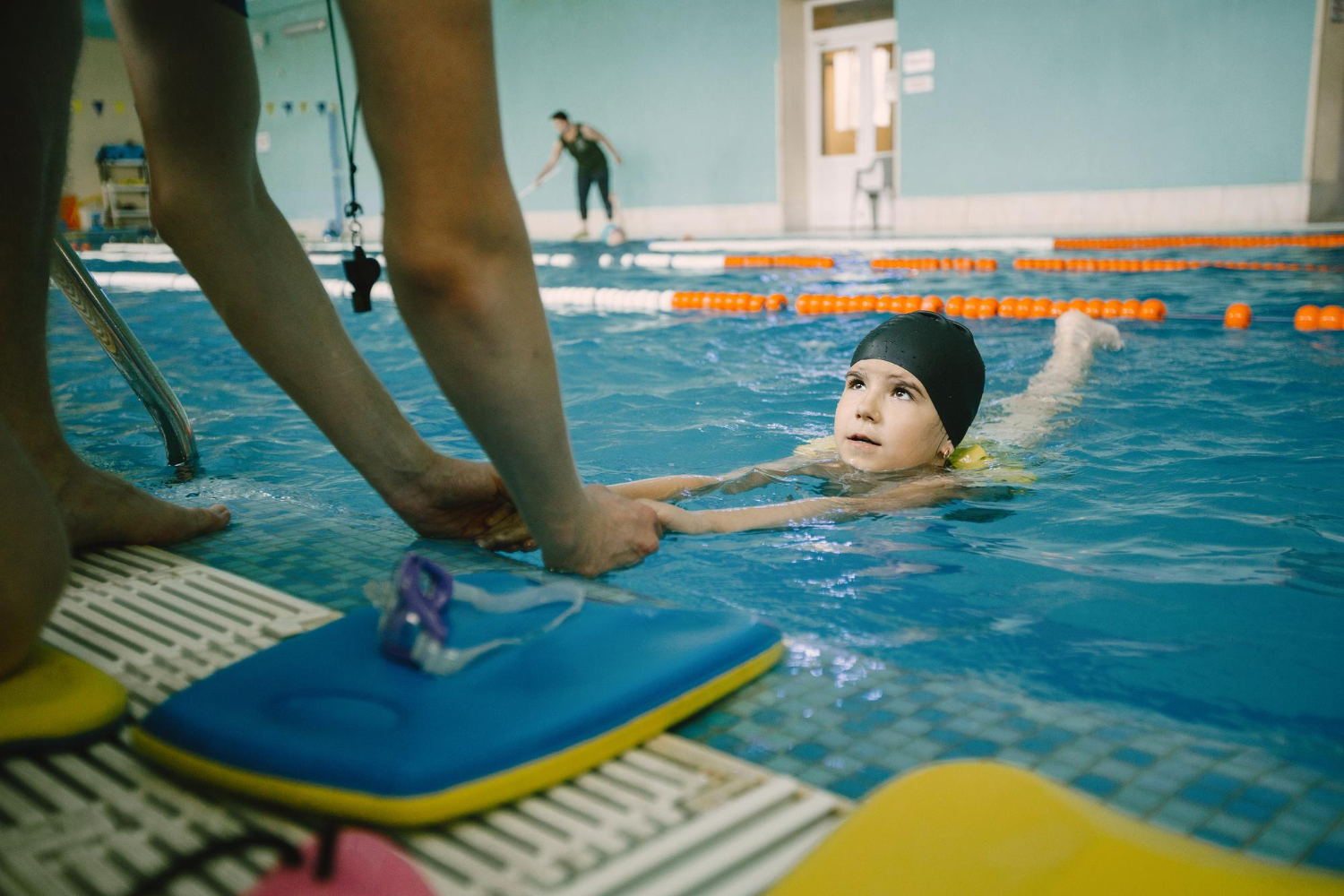 child swimming toward instructor