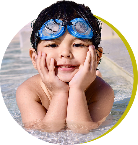 kid relaxing in a pool with goggles on his head about to learn how to swim