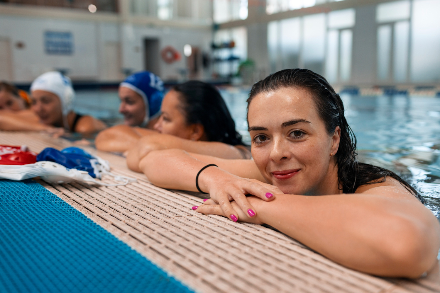 woman smiling on edge of pool with adult swim class behind her