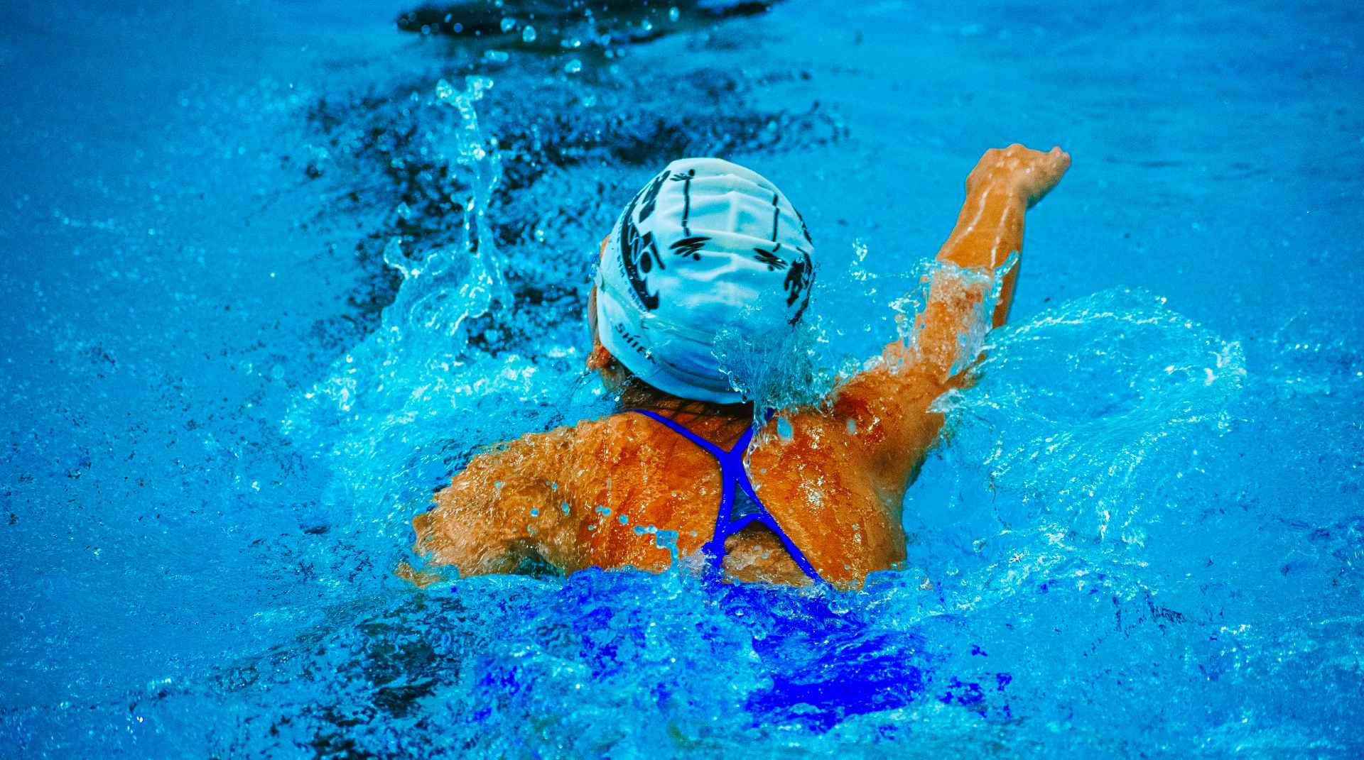 A swimmer swimming in a swimming pool with a cap on and goggles at hudson valley swim