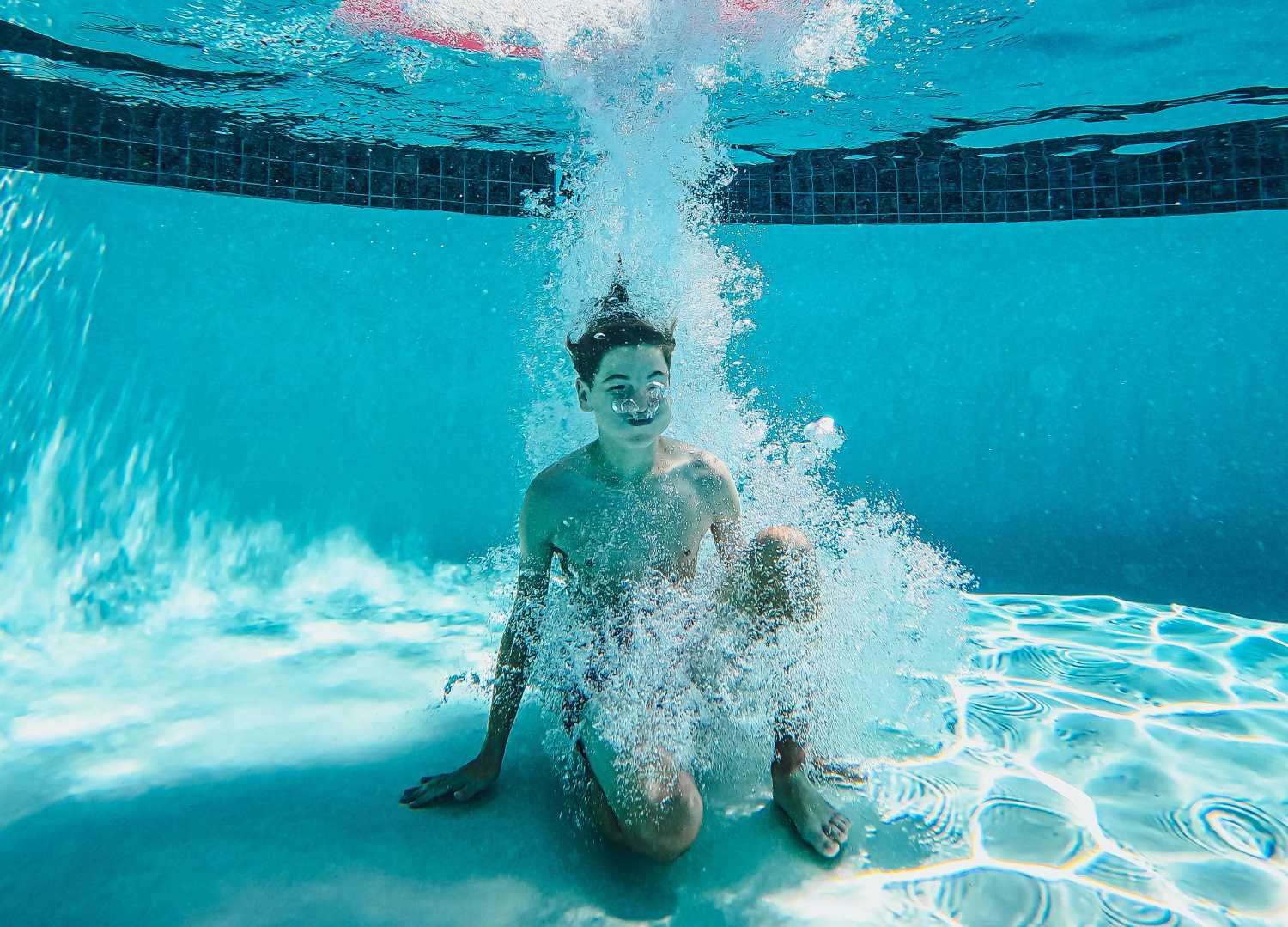 kid jumping into a pool underwater and holding their breath